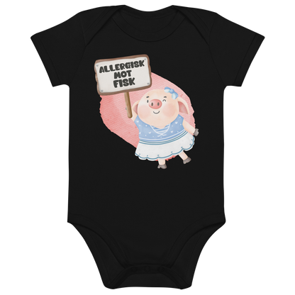 Svart babybody som ligger flatt, med en glad gris som holder oppe et skilt med teksten "Allergisk mot fisk". Foto.