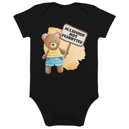 Svart babybody som ligger flatt, med en glad bamse som holder oppe et skilt med teksten "Allergisk mot peanøtter". Foto.