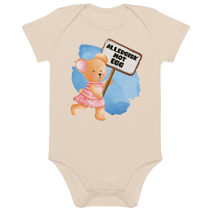 Beige babybody som ligger flatt, med en glad bamse som holder oppe et skilt med teksten "Allergisk mot egg". Foto.