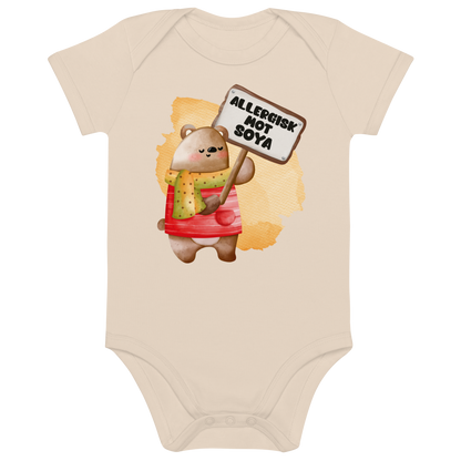 Beige babybody som ligger flatt, med en glad bamse som holder oppe et skilt med teksten "Allergisk mot soya". Foto.