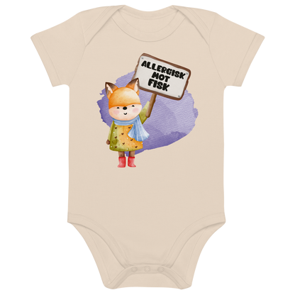 Beige babybody som ligger flatt, med en glad rev som holder oppe et skilt med teksten "Allergisk mot fisk". Foto.