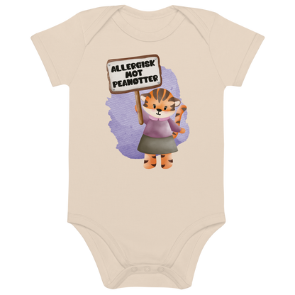 Beige babybody som ligger flatt, med en glad tiger som holder oppe et skilt med teksten "Allergisk mot peanøtter". Foto.