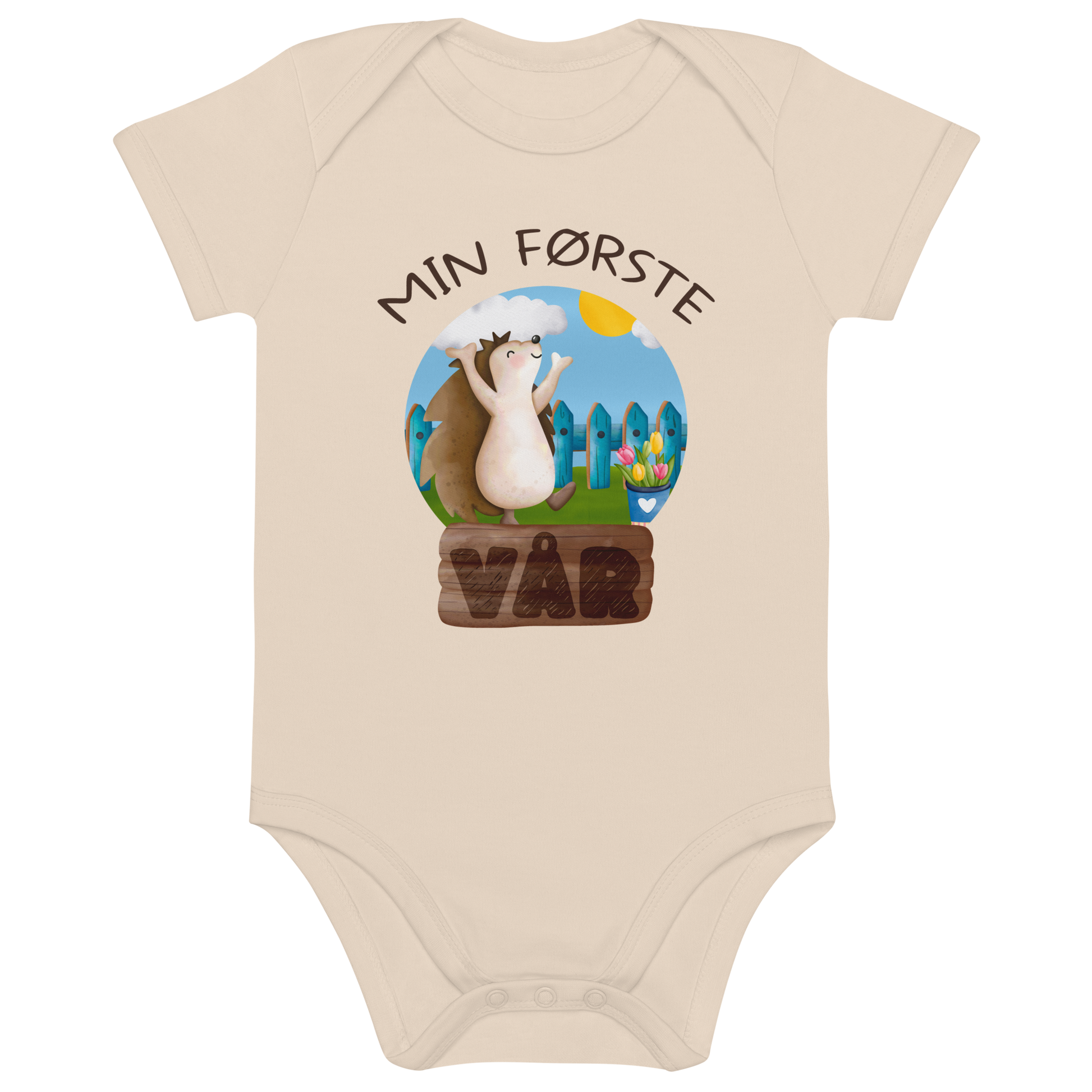 Beige babybody som ligger flatt, med teksten "Min første vår" og figur av et lykkelig pinnsvin som nyter at varmen kommer tilbake. Foto.