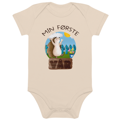 Beige babybody som ligger flatt, med teksten "Min første vår" og figur av et lykkelig pinnsvin som nyter at varmen kommer tilbake. Foto.