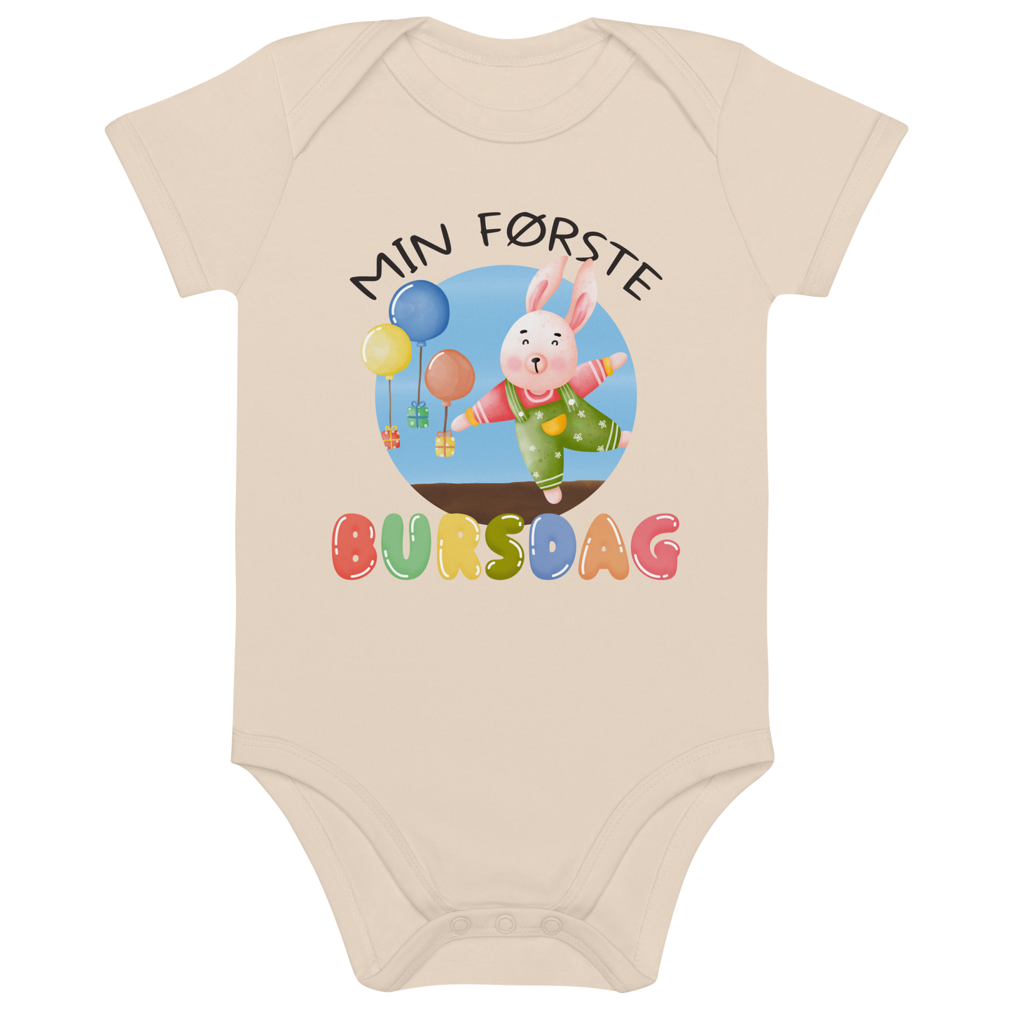 Beige babybody som ligger flatt, med teksten "Min første bursdag" og figur av en glad kanin og gaver som blir holdt oppe i luften av ballonger. Foto.