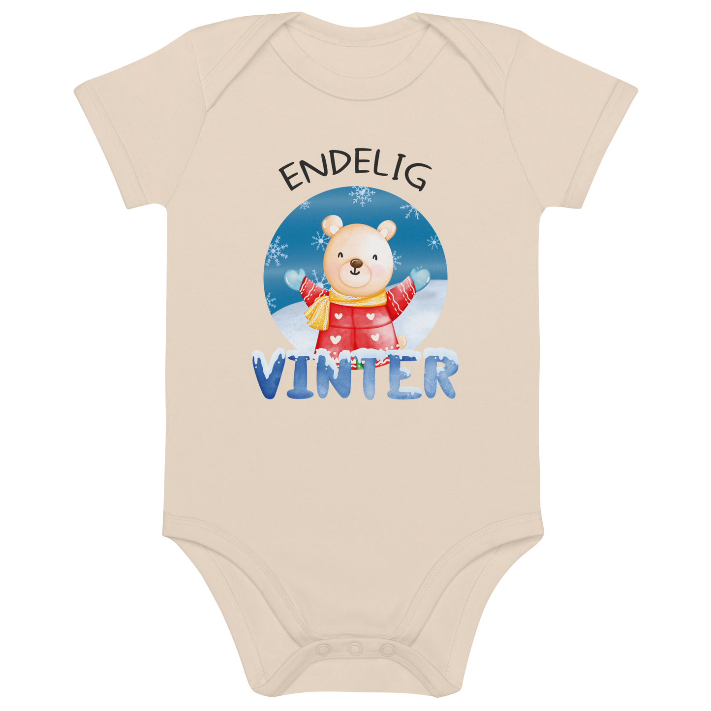 Beige babybody som ligger flatt, med teksten "Endelig vinter" og figur av en lykkelig bamse i vinterklær som nyter snøen. Foto.