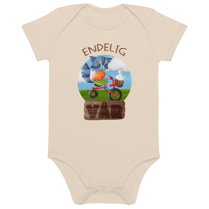 Beige babybody som ligger flatt, med teksten "Endelig vår" og figur av en glad vaskebjørn på sykkel med en fornøyd gås i kurven på styret. Foto.