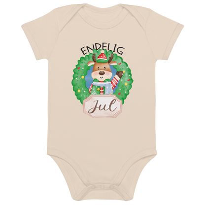 Beige babybody som ligger flatt, med teksten "Endelig jul" og figur av en søt elg i julete klær med en julekrans rundt seg. Foto.