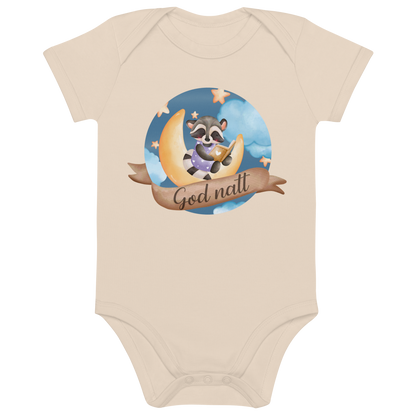 Beige babybody som ligger flatt, med teksten "God natt" og figur av en lykkelig vaskebjørn som sitter på månen og leser en bok. Foto.