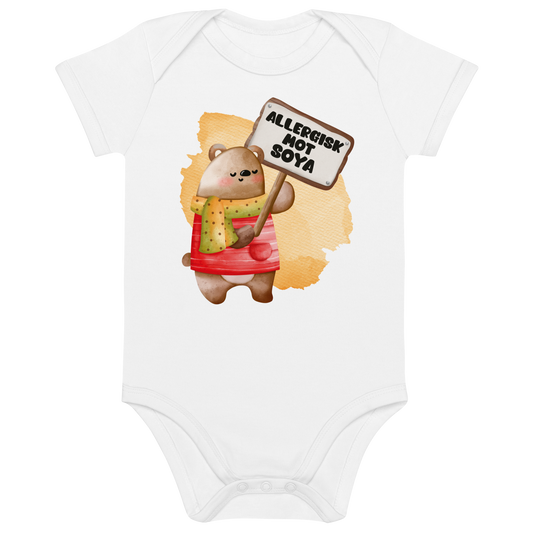 Hvit babybody som ligger flatt, med en glad bamse som holder oppe et skilt med teksten "Allergisk mot soya". Foto.