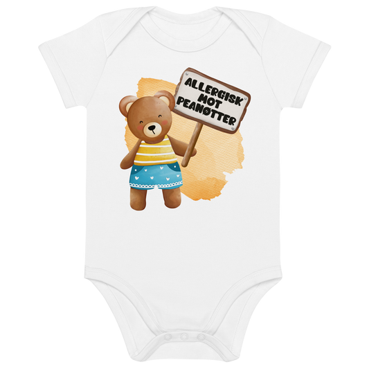 Hvit babybody som ligger flatt, med en glad bamse som holder oppe et skilt med teksten "Allergisk mot peanøtter". Foto.