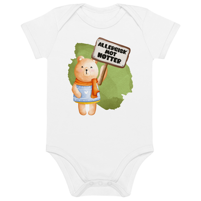 Hvit babybody som ligger flatt, med en glad bamse som holder oppe et skilt med teksten "Allergisk mot nøtter". Foto.