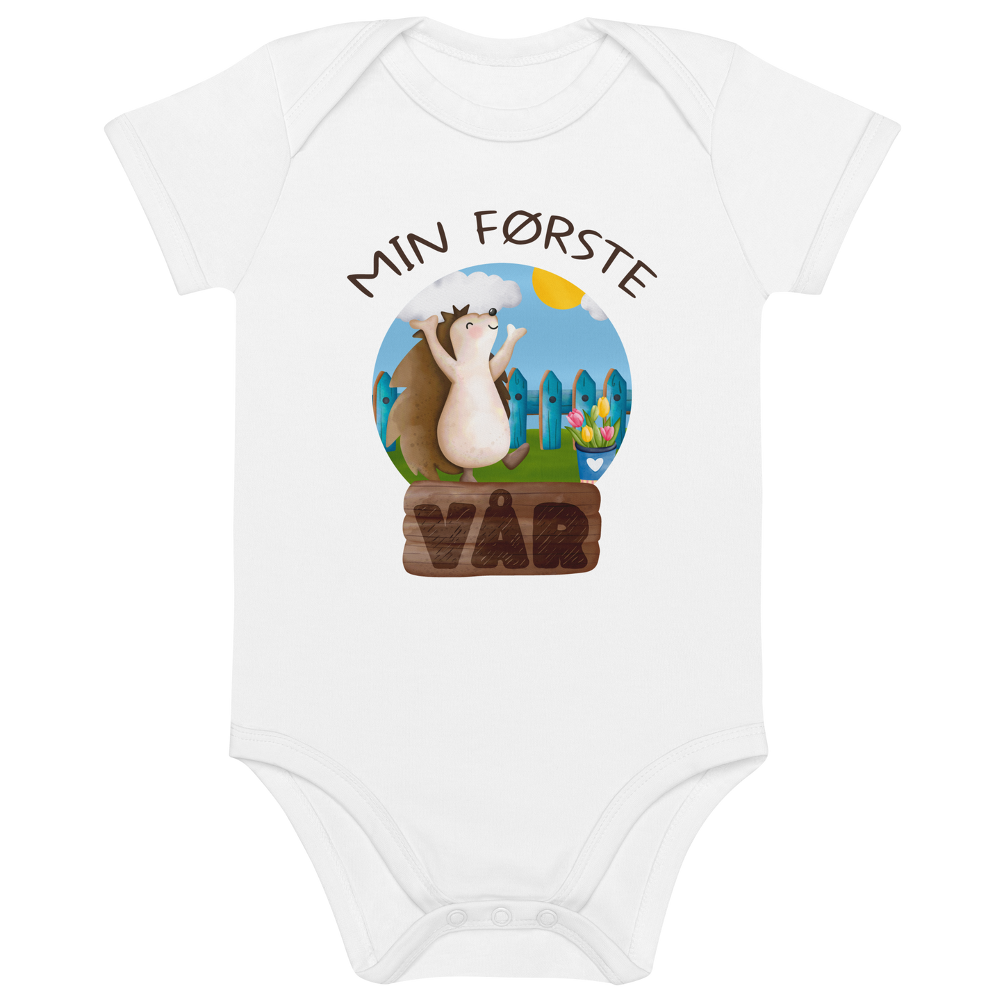 Hvit babybody som ligger flatt, med teksten "Min første vår" og figur av et lykkelig pinnsvin som nyter at varmen kommer tilbake. Foto.