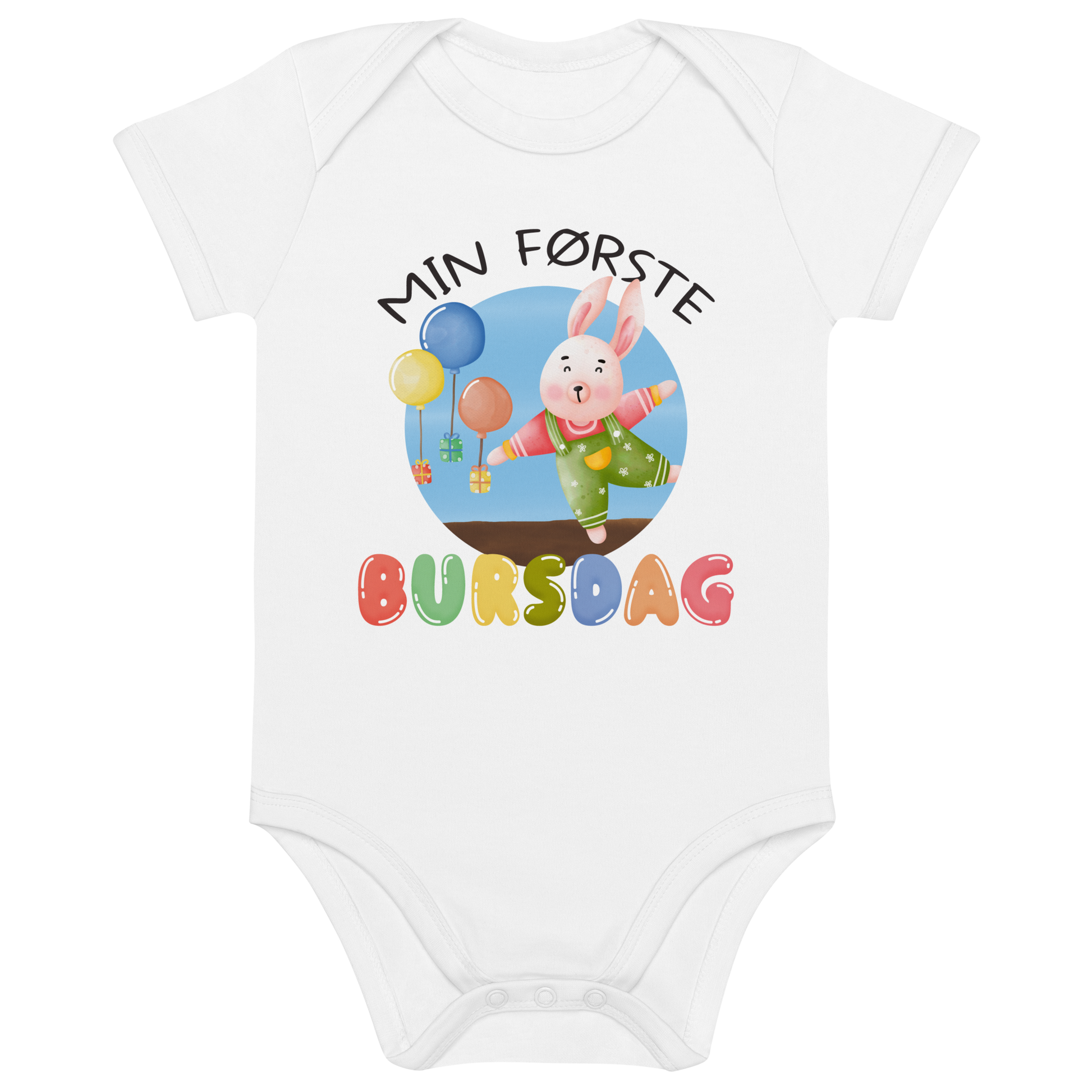 Hvit babybody som ligger flatt, med teksten "Min første bursdag" og figur av en glad kanin og gaver som blir holdt oppe i luften av ballonger. Foto.