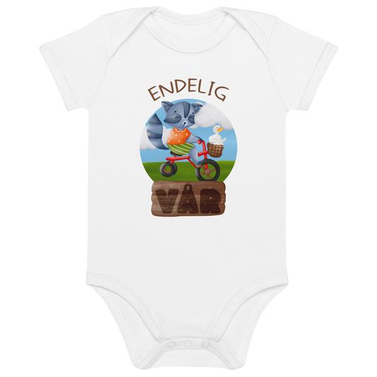 Hvit babybody som ligger flatt, med teksten "Endelig vår" og figur av en glad vaskebjørn på sykkel med en fornøyd gås i kurven på styret. Foto.