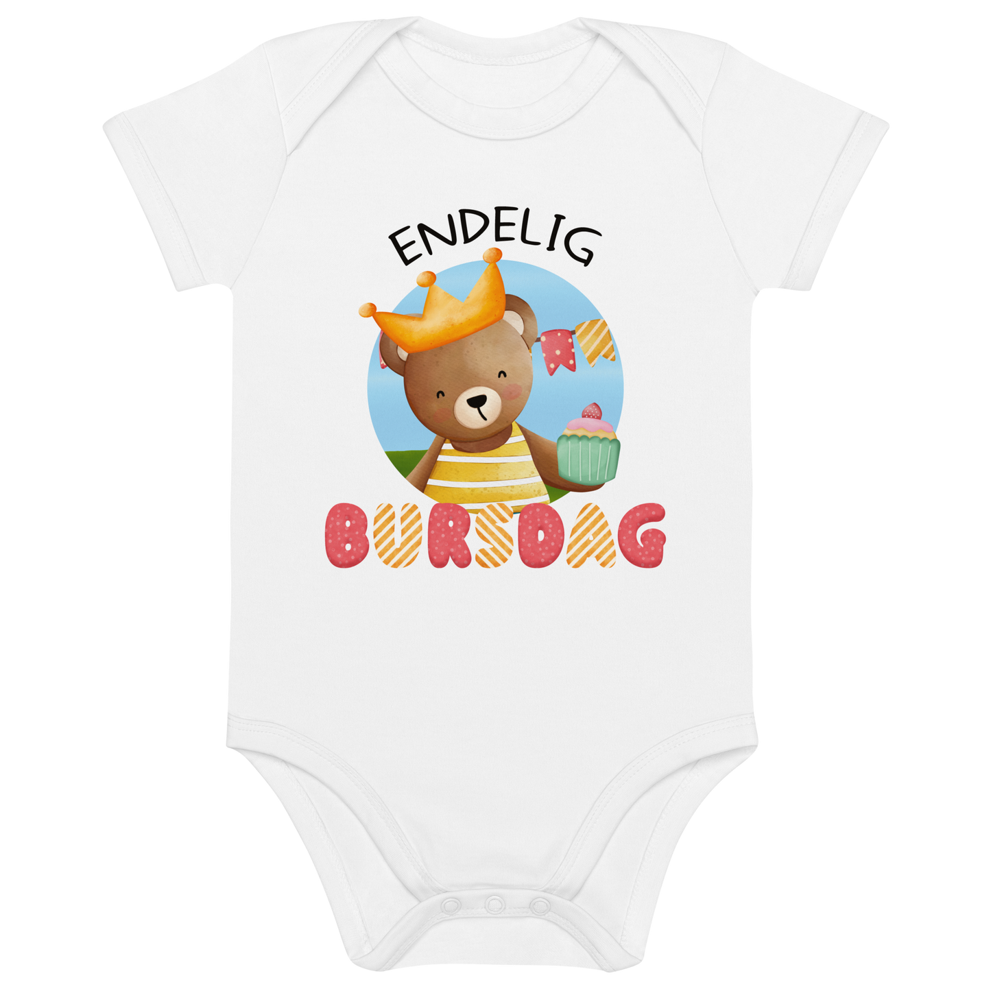 Hvit babybody som ligger flatt, med teksten "Endelig bursdag" og figur av en glad bamse som har på seg en krone og holder frem en muffin. Foto.