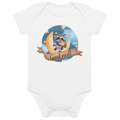 Hvit babybody som ligger flatt, med teksten "God natt" og figur av en lykkelig vaskebjørn som sitter på månen og leser en bok. Foto.