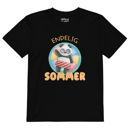 Svart t-skjorte som ligger flatt, med teksten "Endelig sommer" og figur av en avslappet panda med solbriller som flyter i vannet på en badering. Foto.