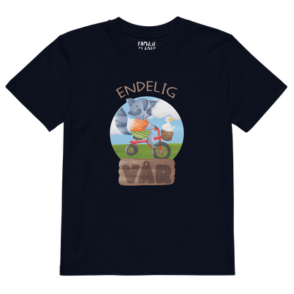 Mørkeblå t-skjorte som ligger flatt, med teksten "Endelig vår" og figur av en glad vaskebjørn på sykkel med en fornøyd gås i kurven på styret. Foto.