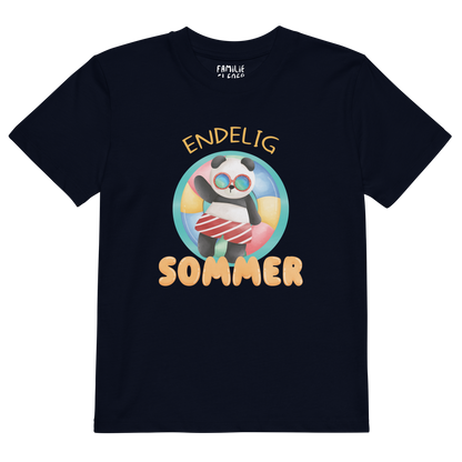 Mørkeblå t-skjorte som ligger flatt, med teksten "Endelig sommer" og figur av en avslappet panda med solbriller som flyter i vannet på en badering. Foto.