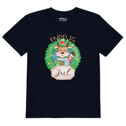 Mørkeblå t-skjorte som ligger flatt, med teksten "Endelig jul" og figur av en søt elg i julete klær med en julekrans rundt seg. Foto.