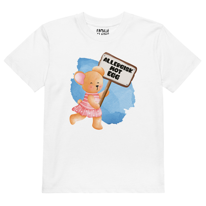 Hvit t-skjorte som ligger flatt, med en glad bamse som holder oppe et skilt med teksten "Allergisk mot egg". Foto.