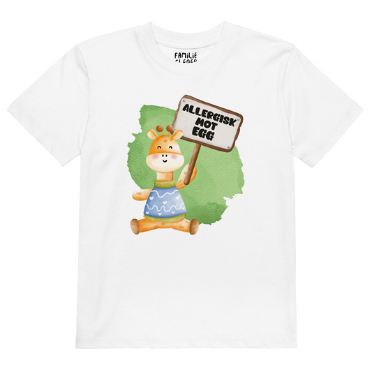 Hvit t-skjorte som ligger flatt, med en glad sjiraff som holder oppe et skilt med teksten "Allergisk mot egg". Foto.