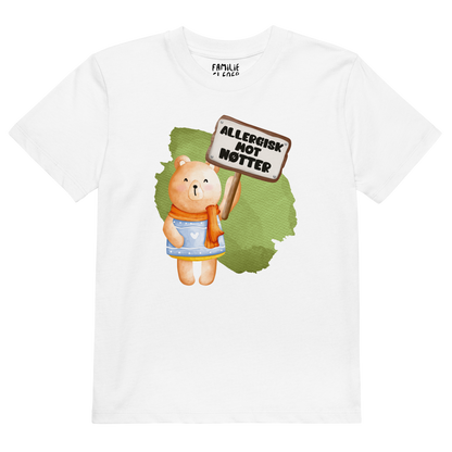 Hvit t-skjorte som ligger flatt, med en glad bamse som holder oppe et skilt med teksten "Allergisk mot nøtter". Foto.