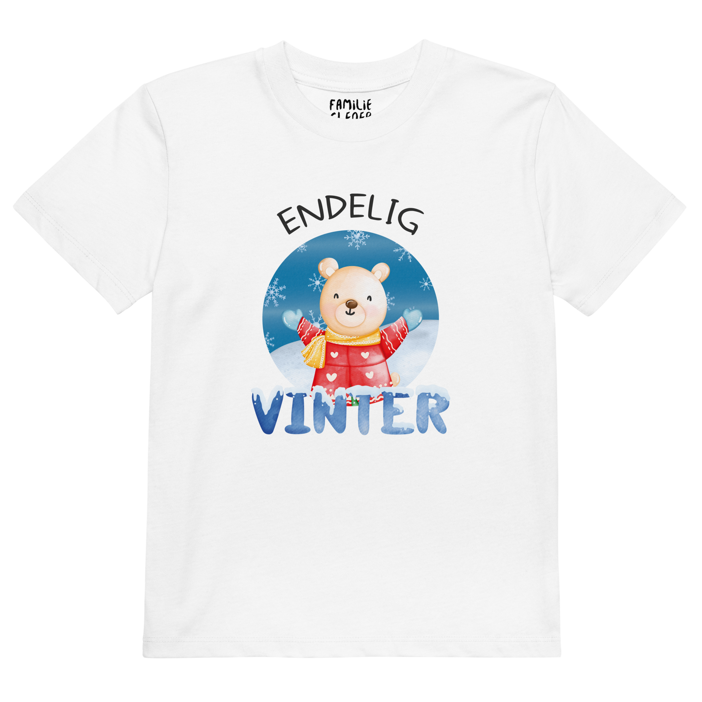 Hvit t-skjorte som ligger flatt, med teksten "Endelig vinter" og figur av en lykkelig bamse i vinterklær som nyter snøen. Foto.