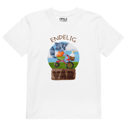 Hvit t-skjorte som ligger flatt, med teksten "Endelig vår" og figur av en glad vaskebjørn på sykkel med en fornøyd gås i kurven på styret. Foto.