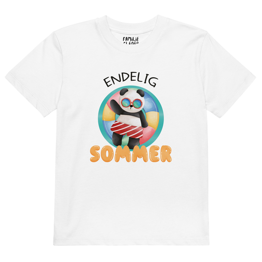 Hvit t-skjorte som ligger flatt, med teksten "Endelig sommer" og figur av en avslappet panda med solbriller som flyter i vannet på en badering. Foto.