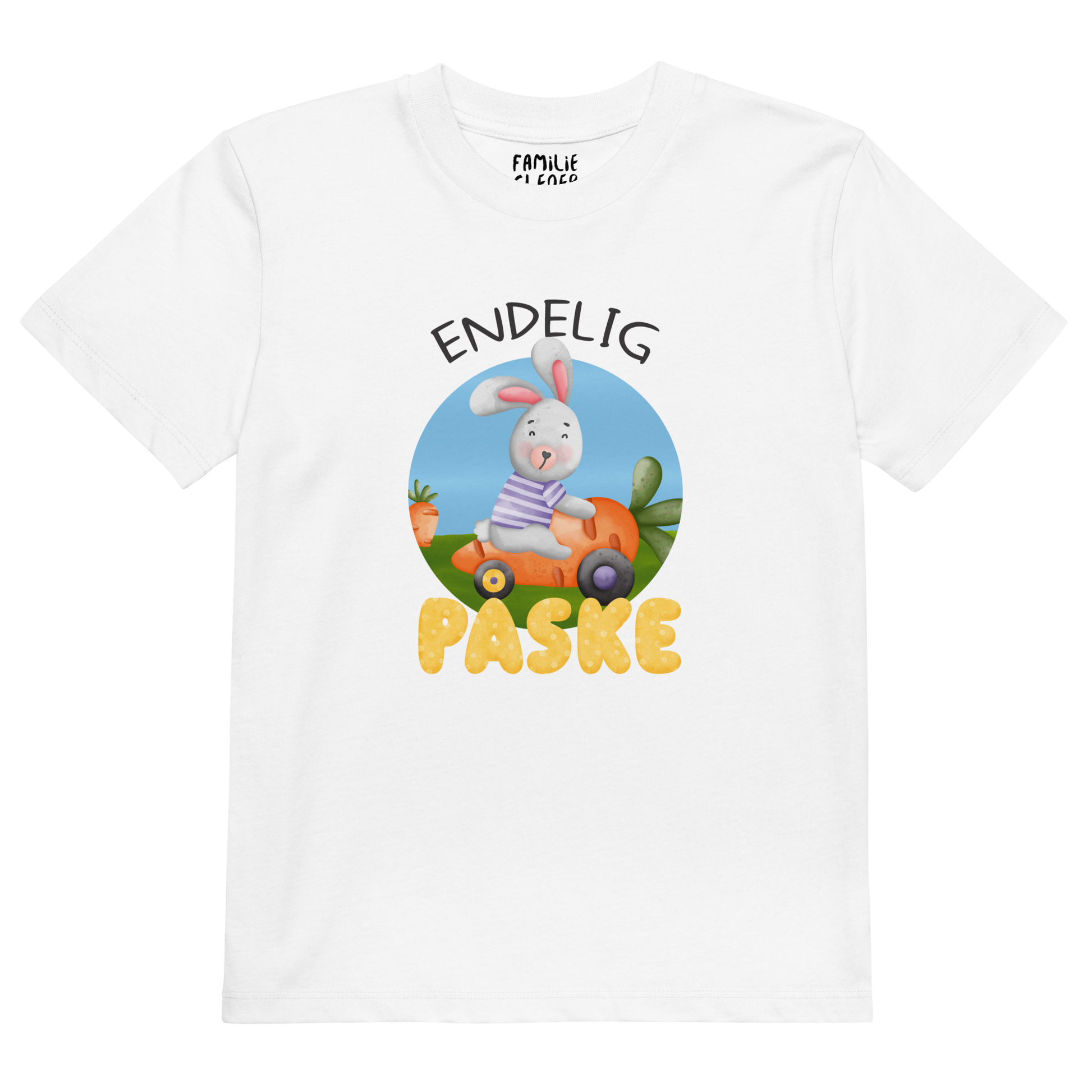 Hvit t-skjorte som ligger flatt, med teksten "Endelig påske" og figur av en glad kanin som kjører en gulrotbil. Foto.