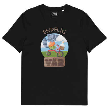 Svart t-skjorte som ligger flatt, med teksten "Endelig vår" og figur av en glad vaskebjørn på sykkel med en fornøyd gås i kurven på styret. Foto.