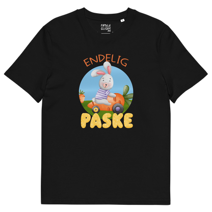 Svart t-skjorte som ligger flatt, med teksten "Endelig påske" og figur av en glad kanin som kjører en gulrotbil. Foto.