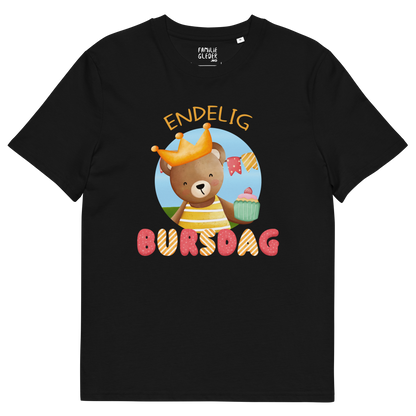 Svart t-skjorte som ligger flatt, med teksten "Endelig bursdag" og figur av en glad bamse som har på seg en krone og holder frem en muffin. Foto.