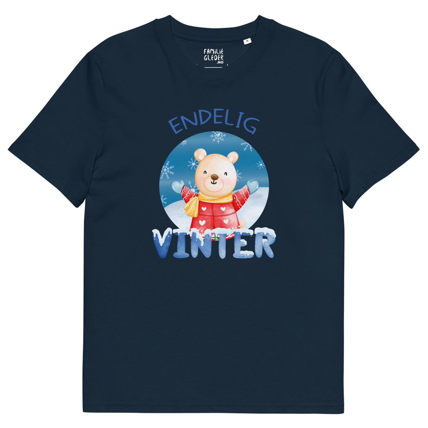 Mørkeblå t-skjorte som ligger flatt, med teksten "Endelig vinter" og figur av en lykkelig bamse i vinterklær som nyter snøen. Foto.
