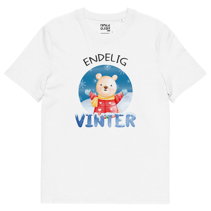 Hvit t-skjorte som ligger flatt, med teksten "Endelig vinter" og figur av en lykkelig bamse i vinterklær som nyter snøen. Foto.