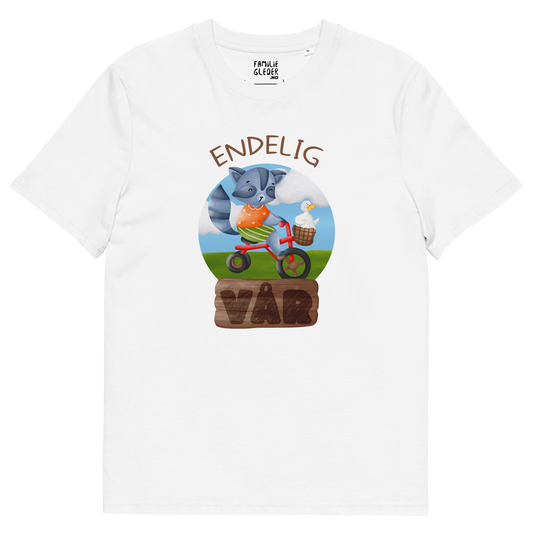Hvit t-skjorte som ligger flatt, med teksten "Endelig vår" og figur av en glad vaskebjørn på sykkel med en fornøyd gås i kurven på styret. Foto.