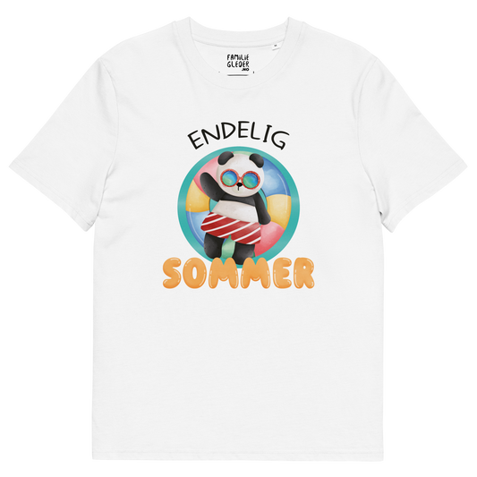 Hvit t-skjorte som ligger flatt, med teksten "Endelig sommer" og figur av en avslappet panda med solbriller som flyter i vannet på en badering. Foto.