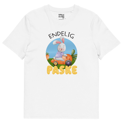 Hvit t-skjorte som ligger flatt, med teksten "Endelig påske" og figur av en glad kanin som kjører en gulrotbil. Foto.