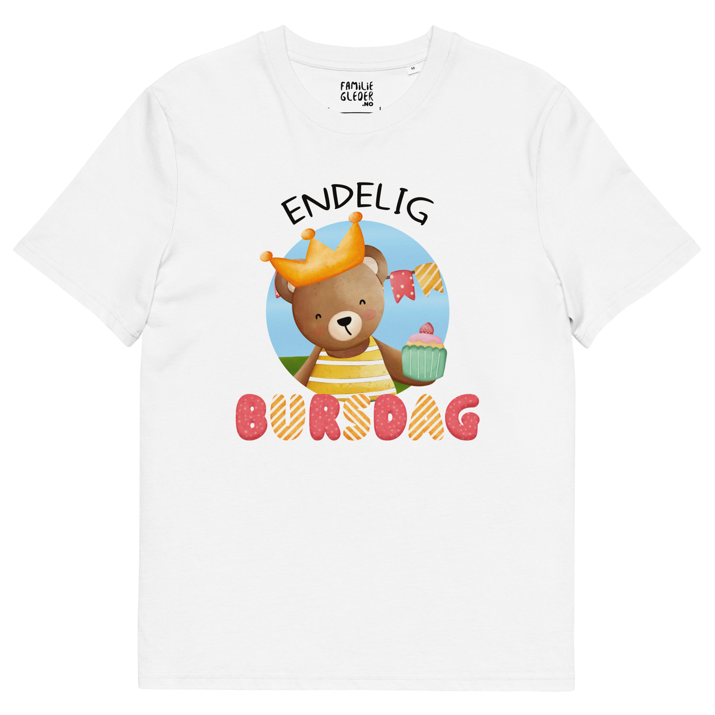 Hvit t-skjorte som ligger flatt, med teksten "Endelig bursdag" og figur av en glad bamse som har på seg en krone og holder frem en muffin. Foto.